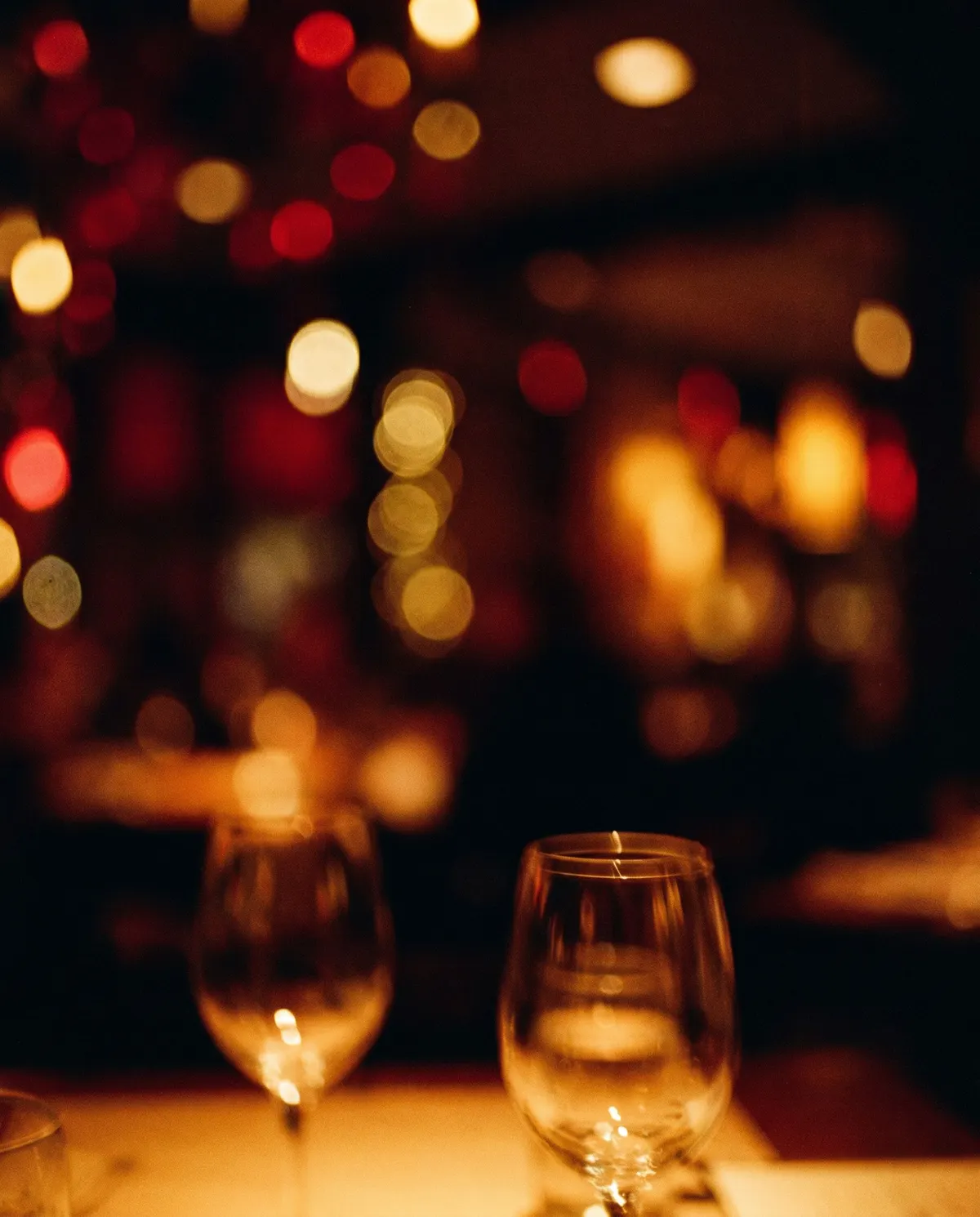 Warm bokeh and wine glasses, dim restaurant